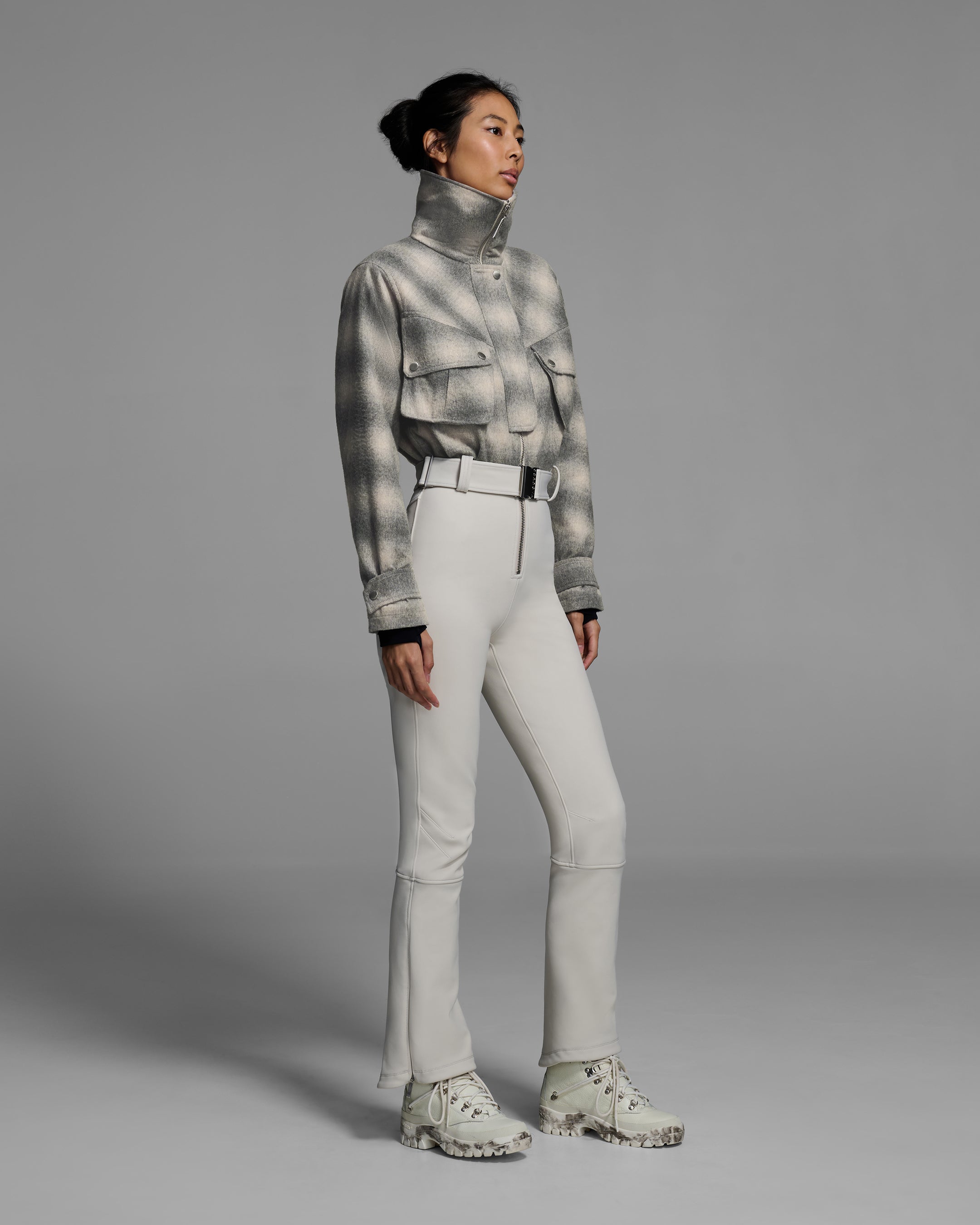 Woman wearing a natural white and grey plaid color wool top ski suit with belted waist and smoke colored 4-way stretch bottom. #color_plaid smoke / stone