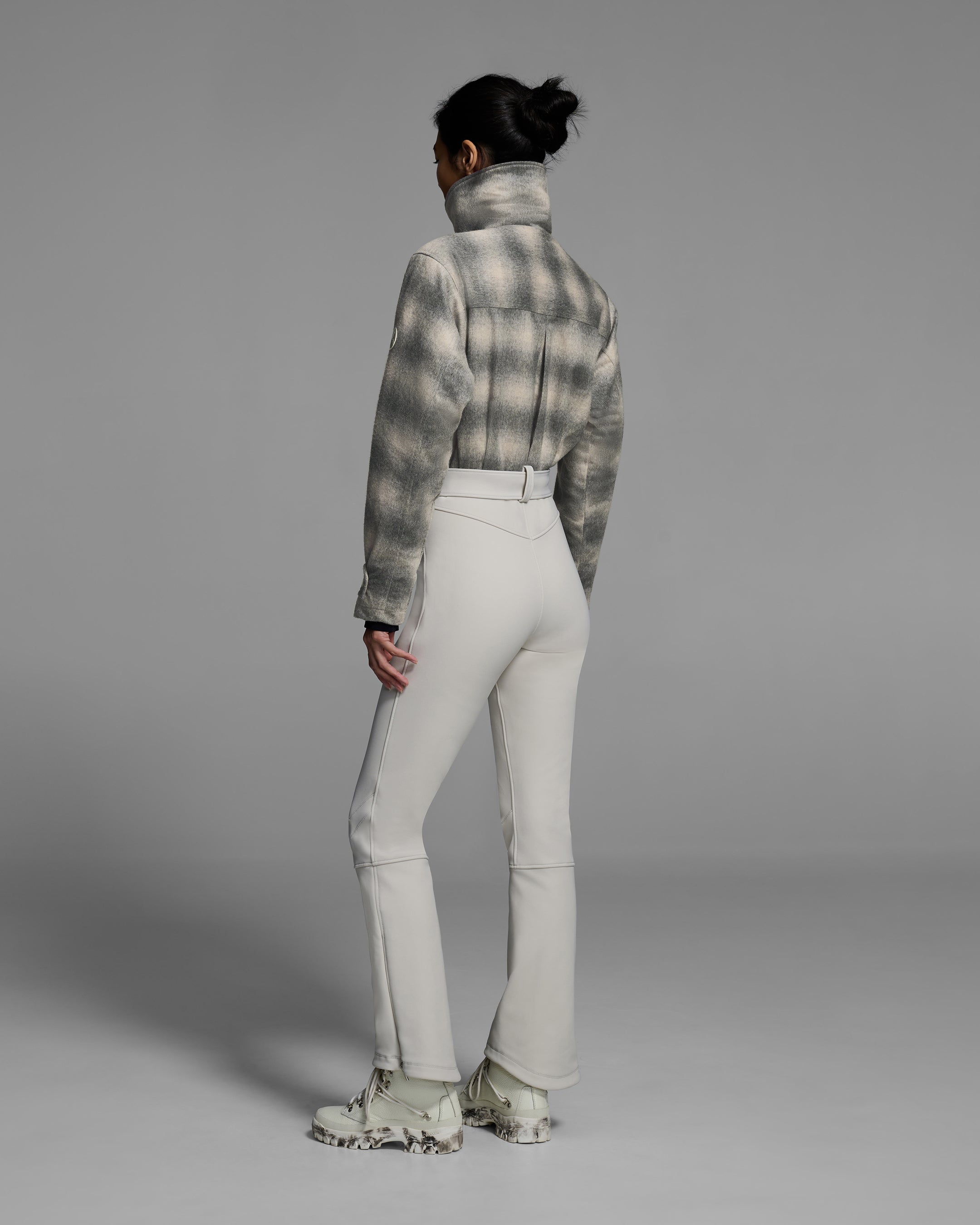Back view of a woman wearing a natural white and grey plaid color wool top ski suit with belted waist and smoke colored 4-way stretch bottom. #color_plaid smoke / stone