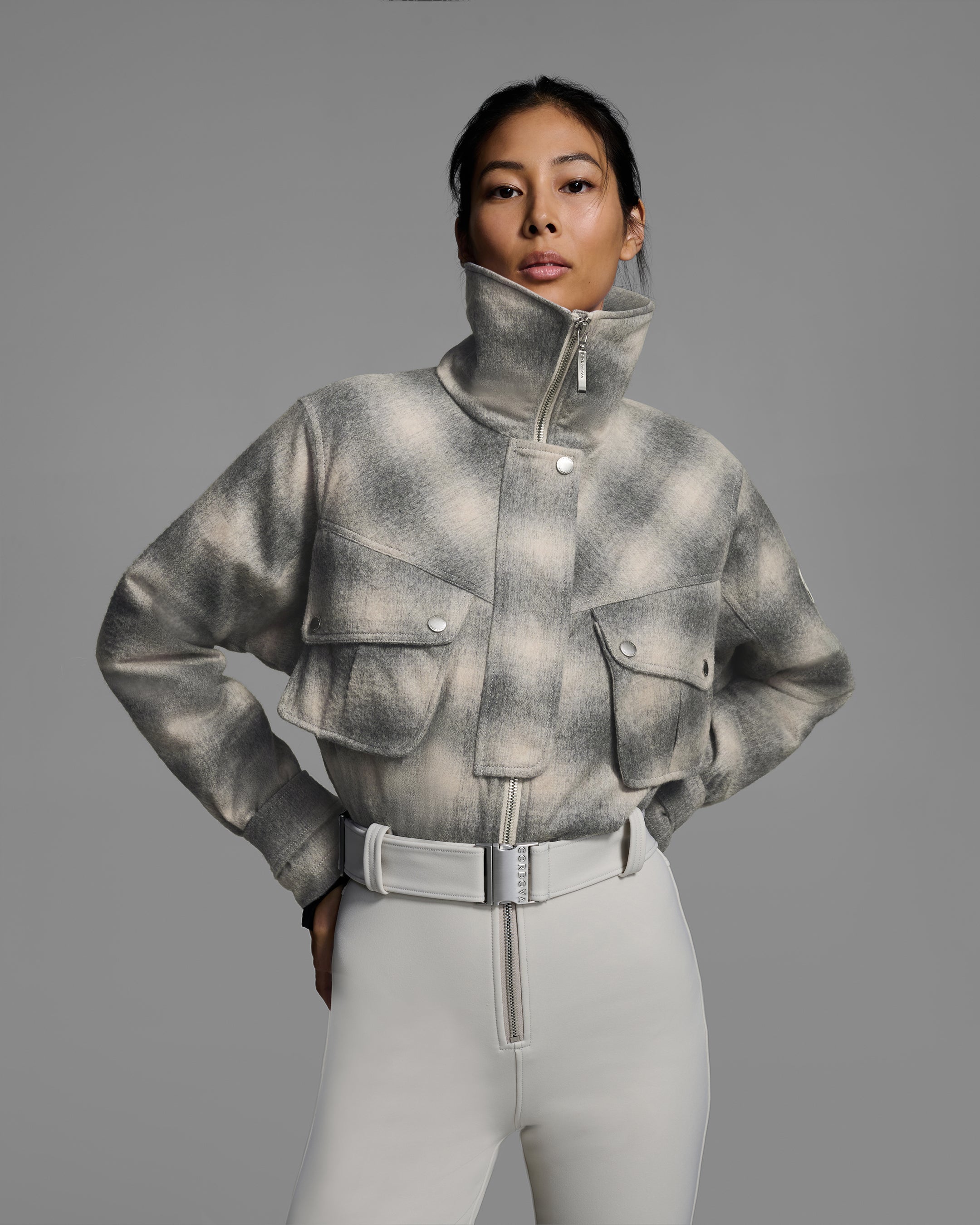 Detail front view of a woman wearing a natural white and grey plaid color wool top ski suit with belted waist and smoke color 4-way stretch bottom. #color_wool plaid / smoke