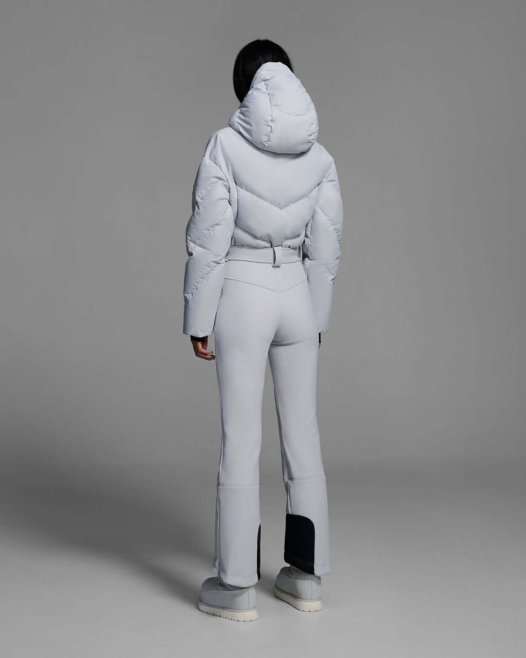 Back view of a female model wearing a belted smoke gray color ski suit with down filled top and 4-way stretch bottom. #color_smoke