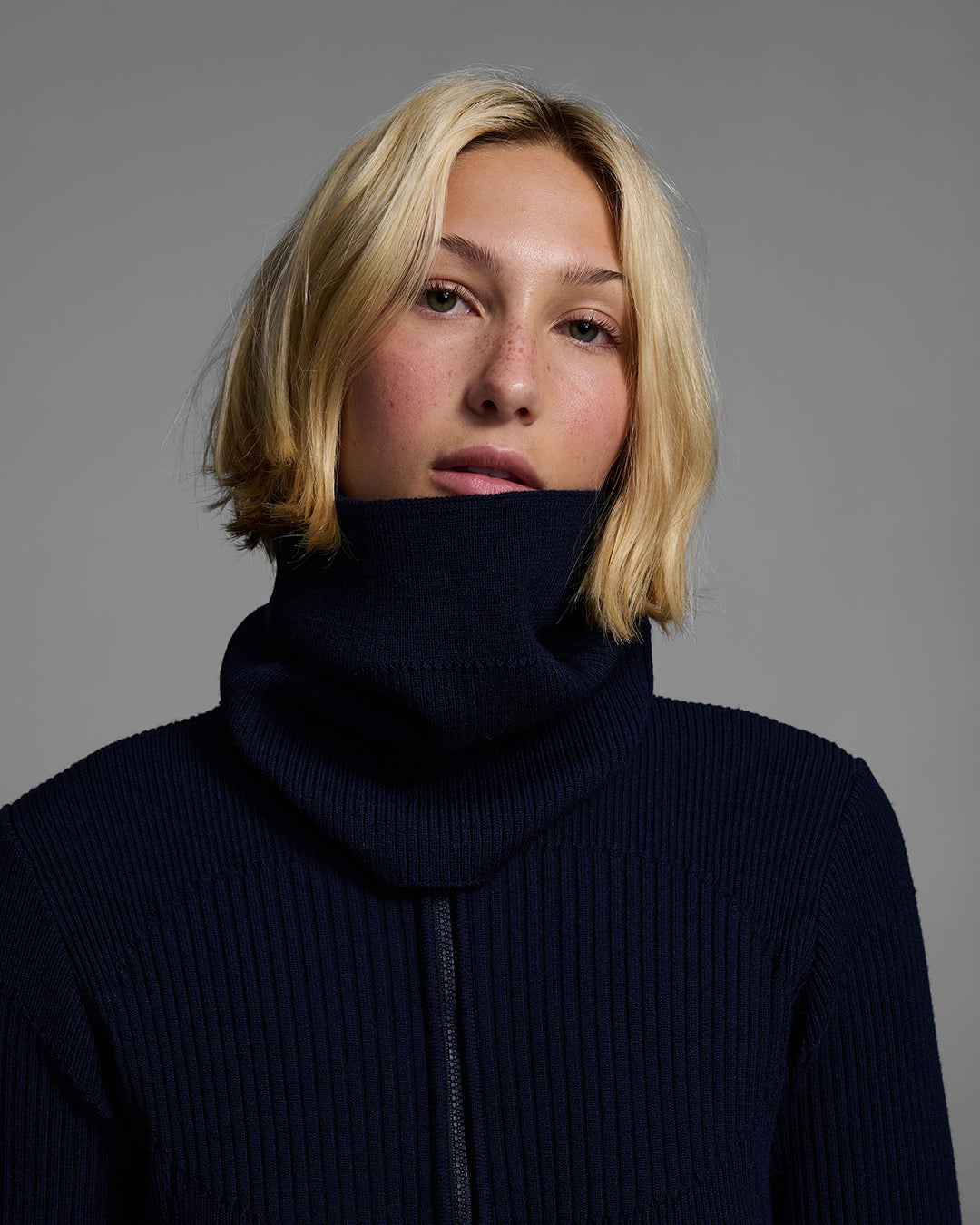 Front detail view of a female model wearing a knit wool buff in indigo blue with matching bodysuit. #color_indigo