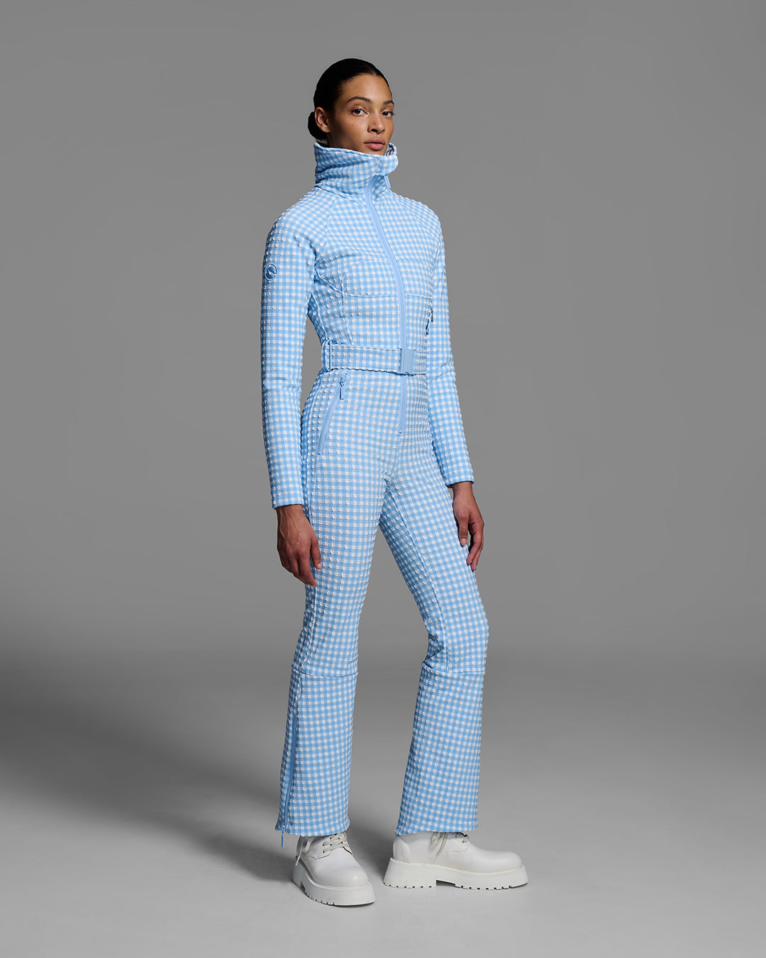 Female model wearing a belted cerulean blue and white gingham print ski suit #color_cerulean gingham
