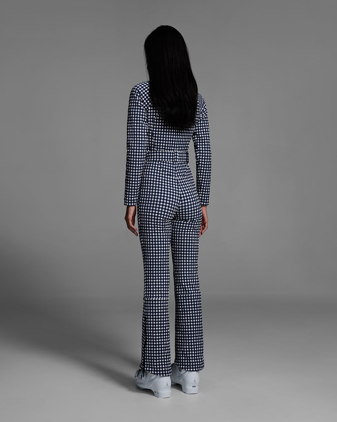 Back view of a female model wearing a belted indigo blue and white gingham print ski suit #color_indigo gingham