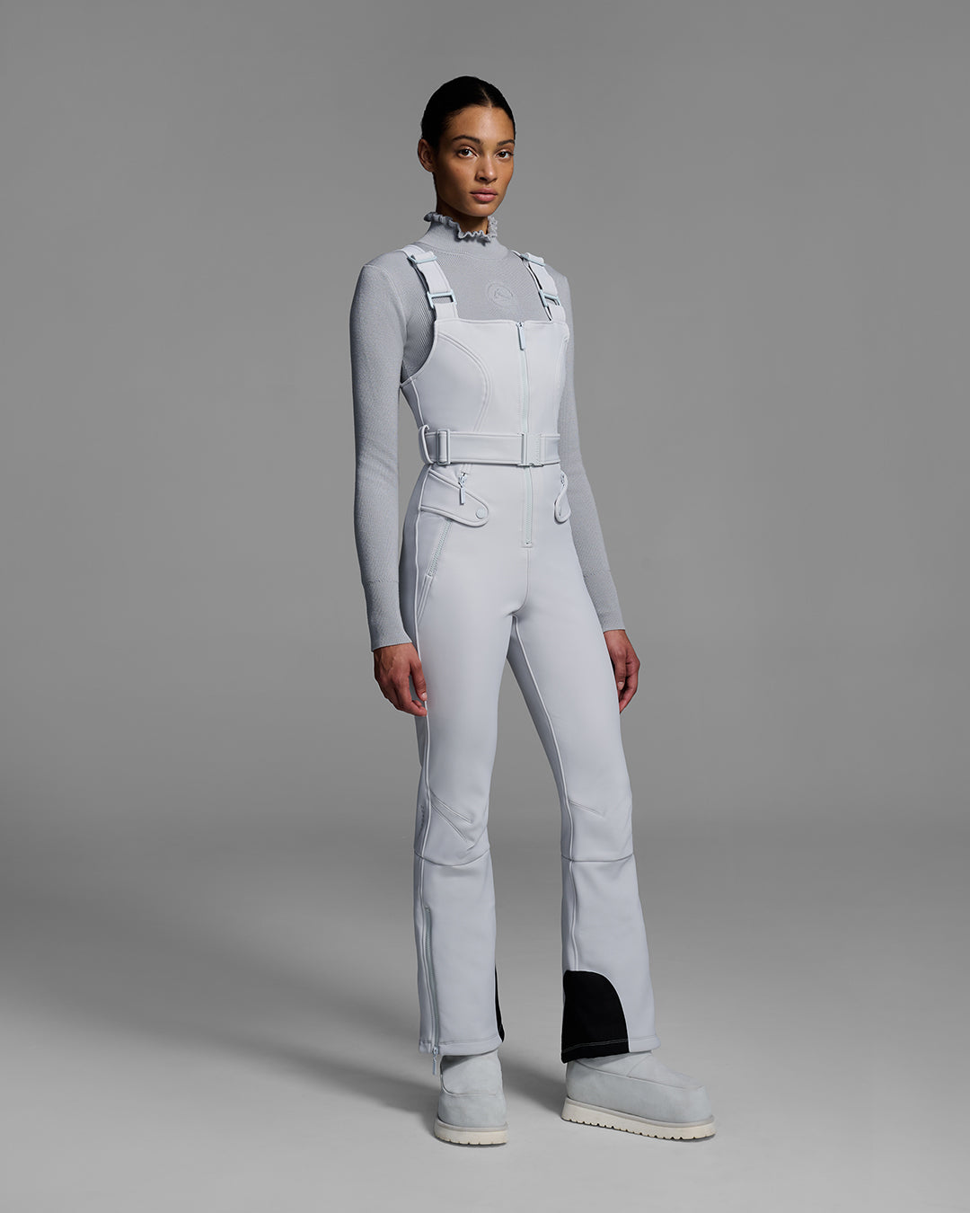 Female model wearing a belted smoke gray color ski bib with matching gray sweater. #color_smoke