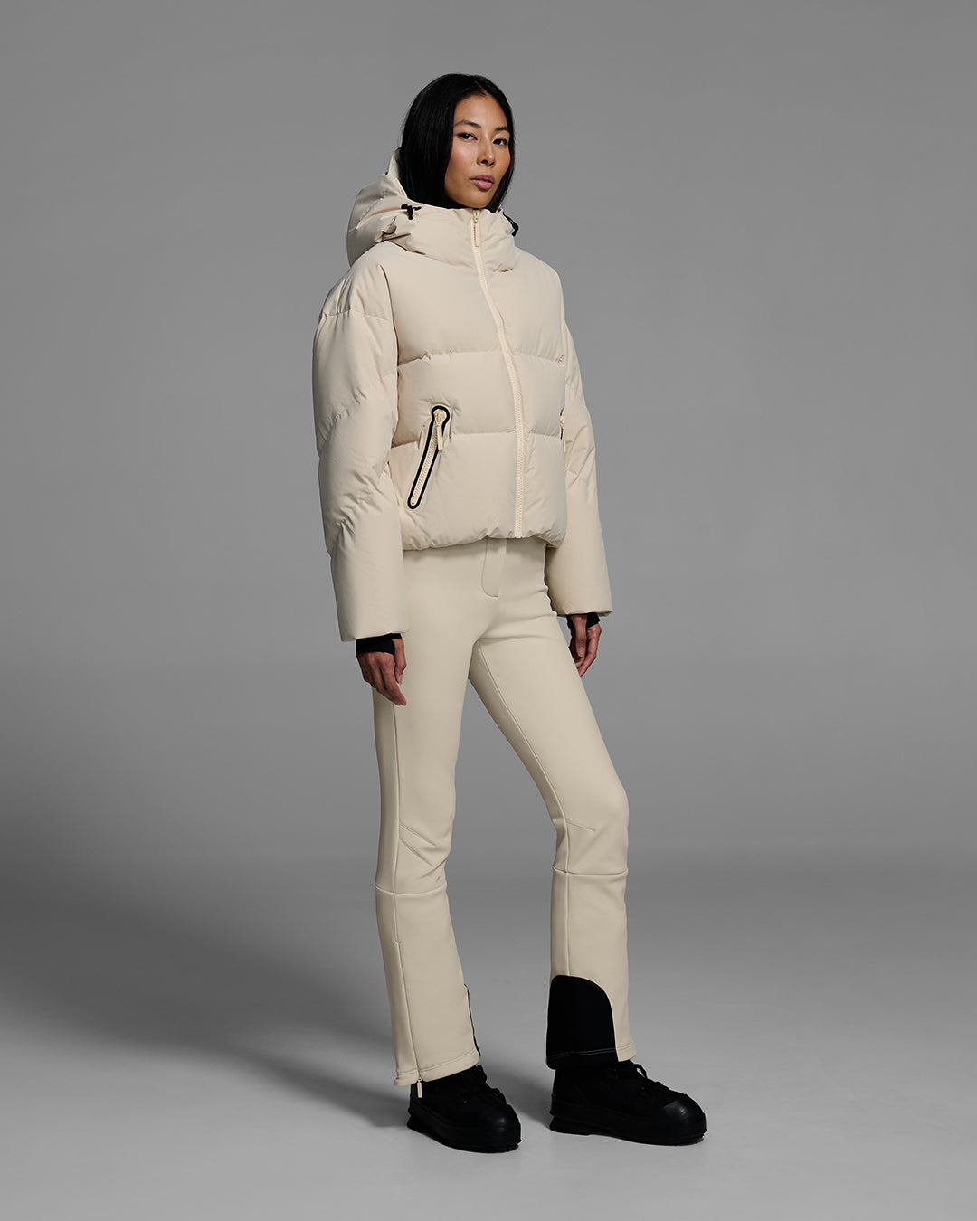 Female model wearing a classic down filled ski jacket in birch inspired tan with a matching ski pant. #color_birch