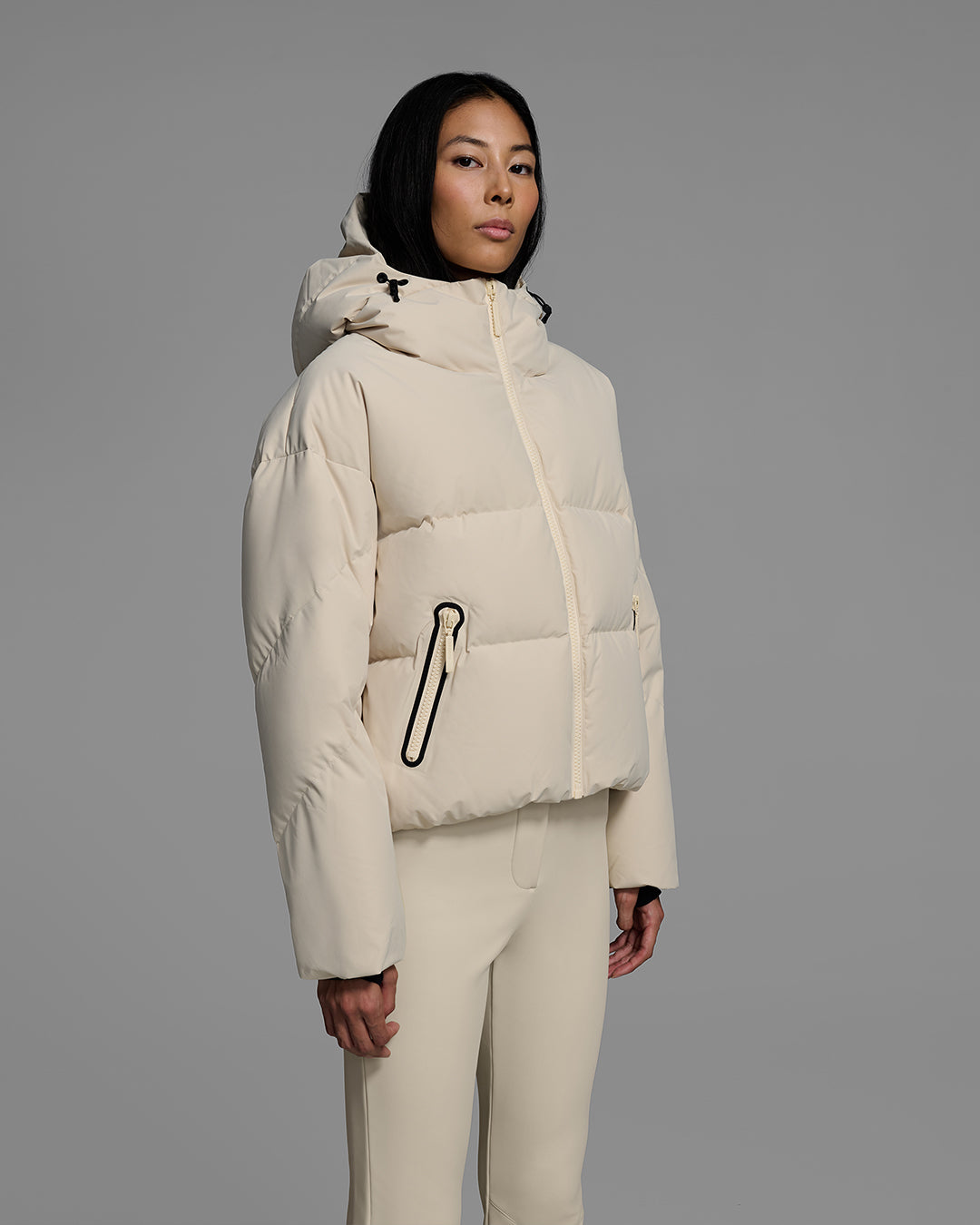 Knee up detail shot of a female model wearing a classic down filled ski jacket in birch inspired tan with a matching ski pant. #color_birch