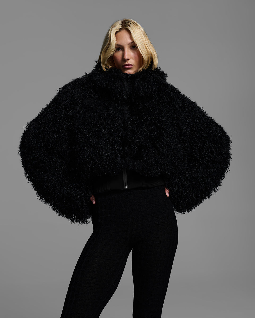 Female model wearing a black color shearling jacket with matching ski pant. #color_onyx