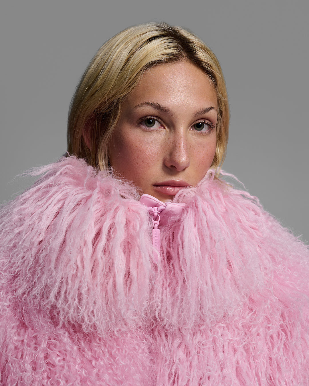 Detail view of the shearling collar of a female model wearing a natural shearling jacket in peony pink. #color_peony