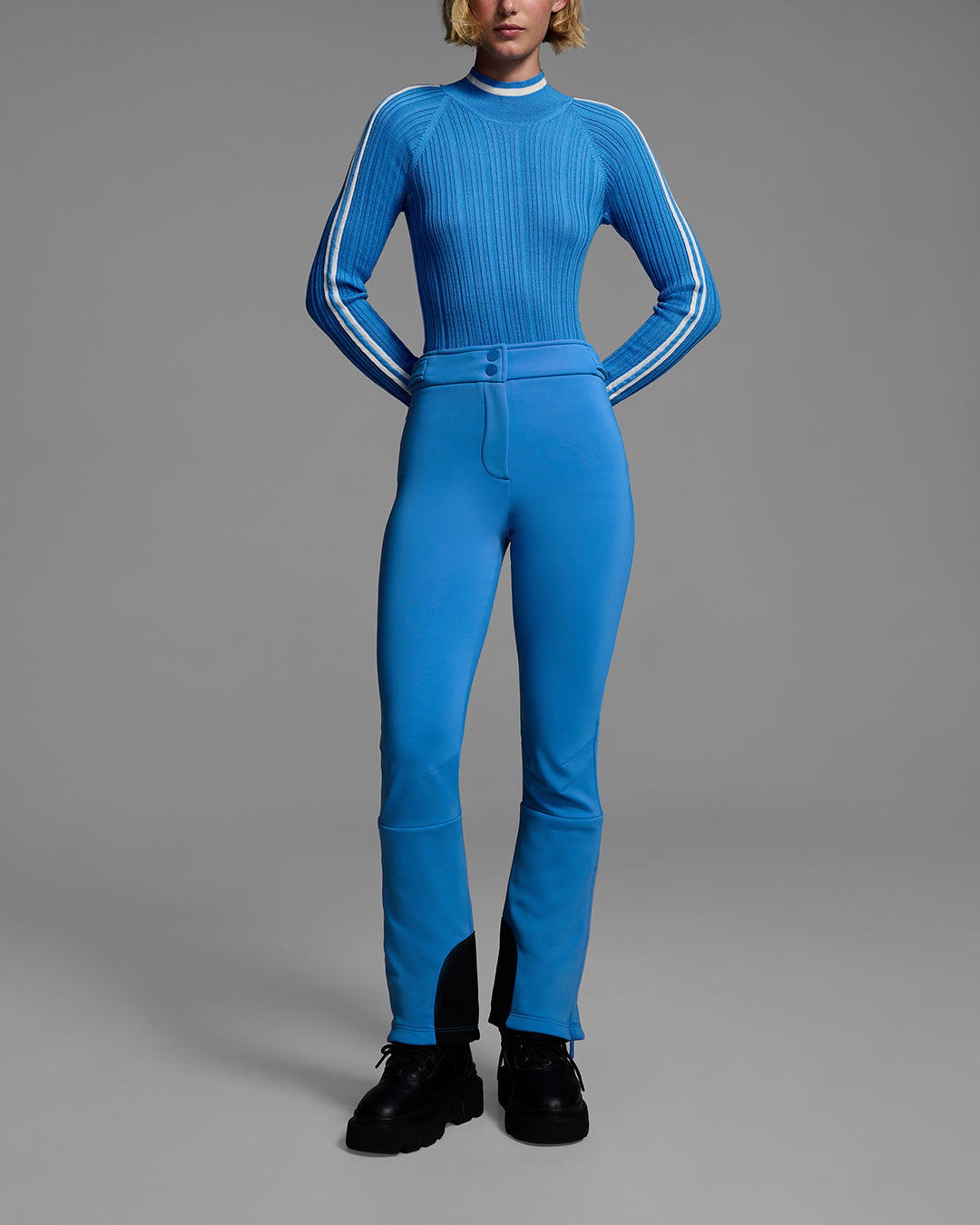 Front view of a woman wearing a 4-way stretch ski pant in bright blue and a matching ski sweater with a racing stripes on the sleeves. #color_azul