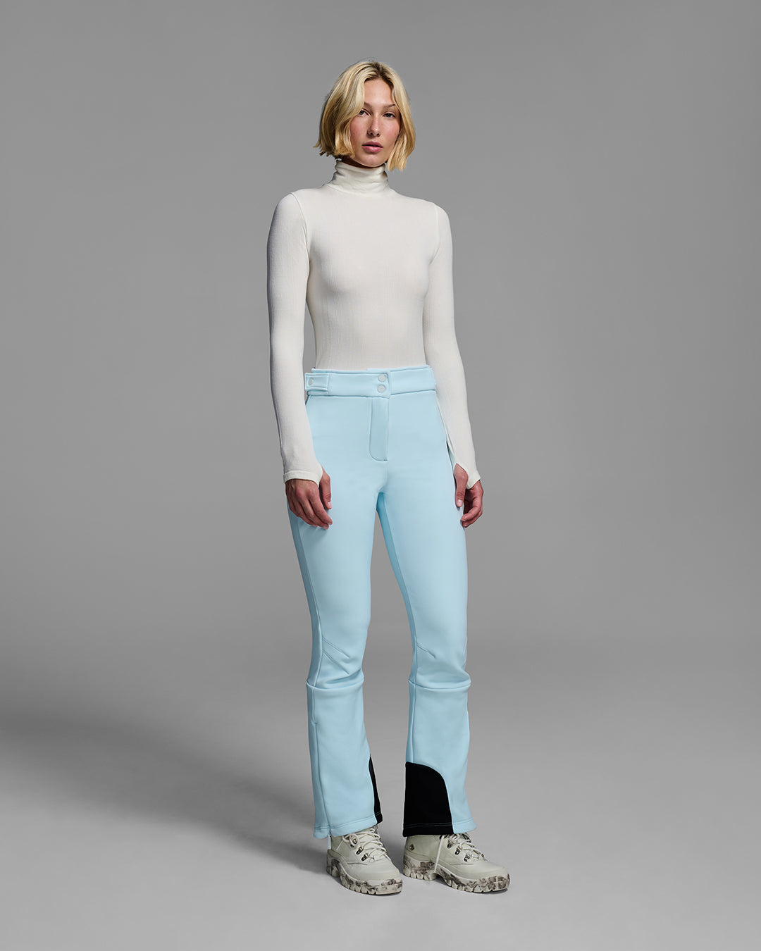 Woman wearing a 4-way stretch ski pant in iceberg blue and a white base layer top. #color_iceberg