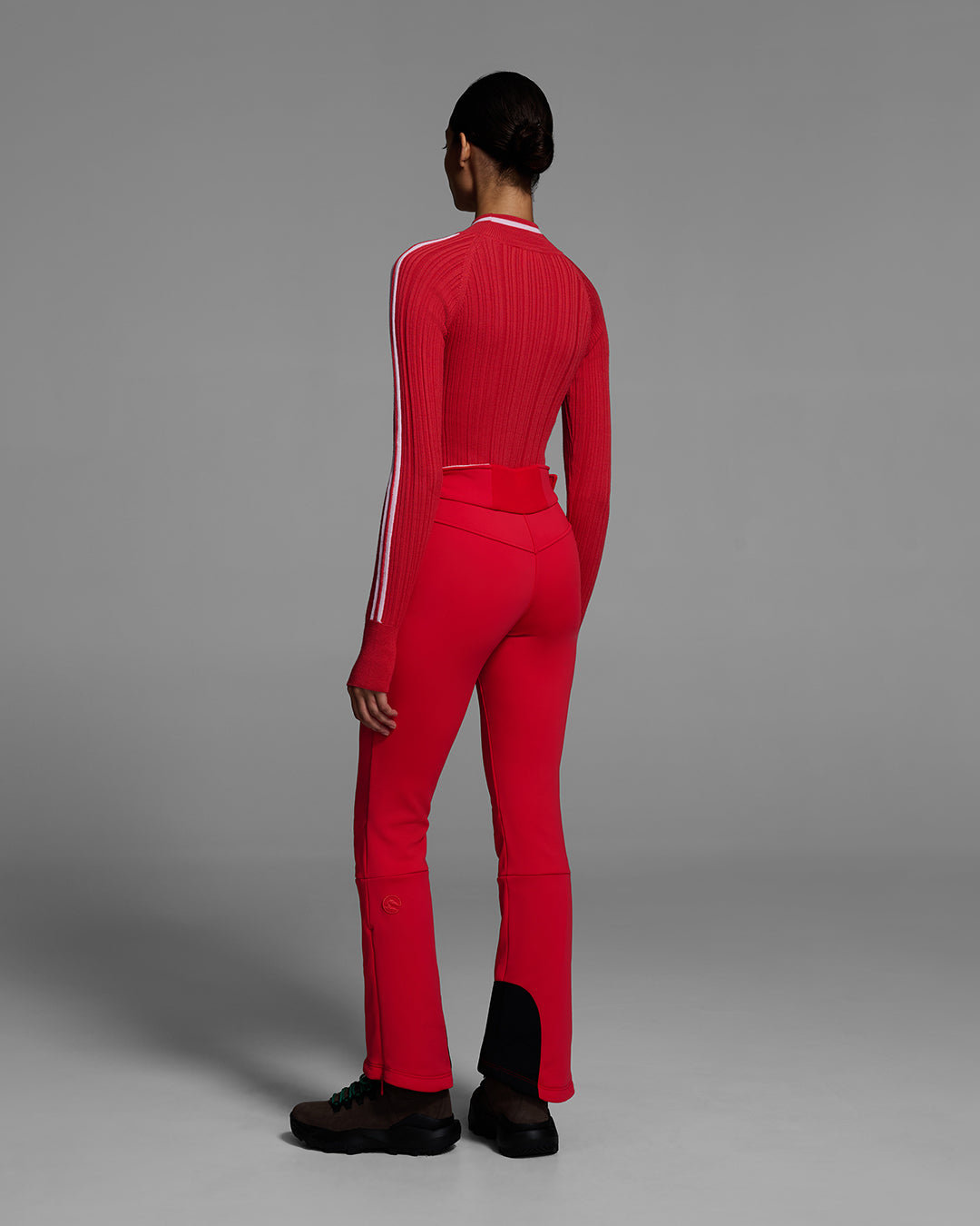Back view of a woman wearing a 4-way stretch ski pant in poppy red and a matching red ski sweater. #color_poppy