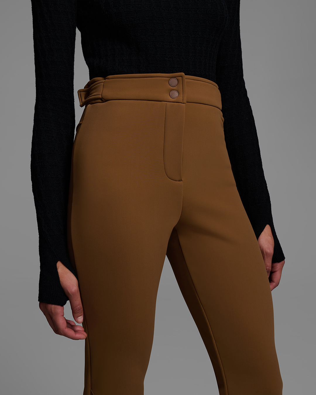 Detail view of the waist of a woman wearing a 4-way stretch ski pant in sepia brown and a black base layer top. #color_sepia