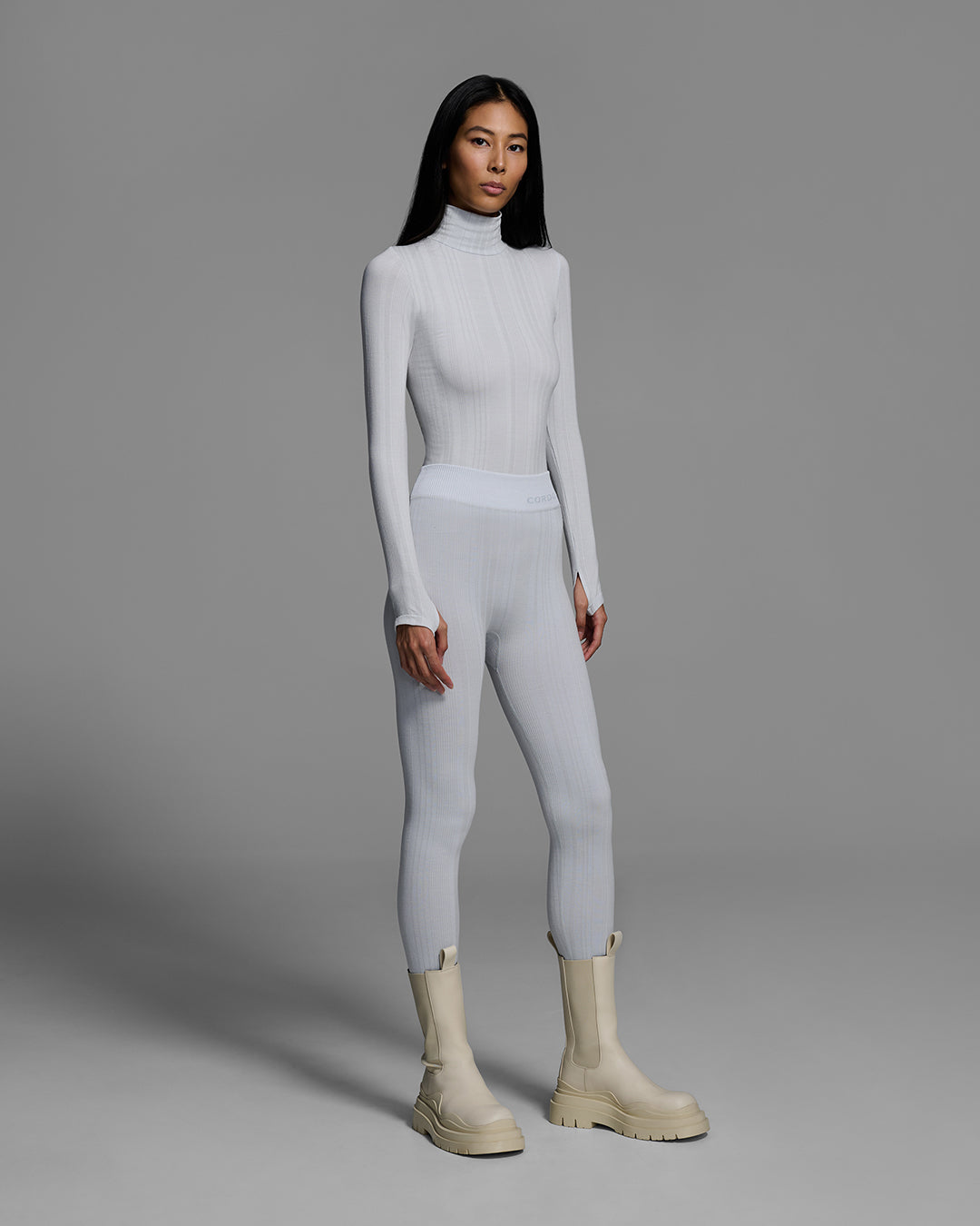 Woman wearing a smoke gray color turtleneck and matching pant base layer set made of merino wool blend. #color_smoke