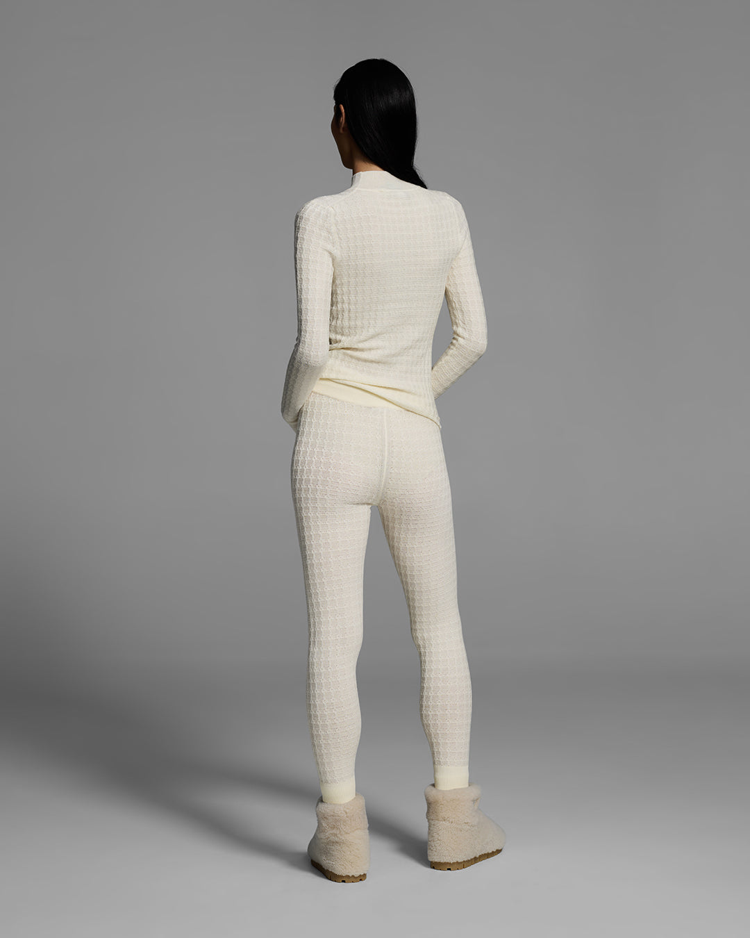 Back view of a woman wearing a textural knit base layer top and bottom in off-white. #color_alabaster