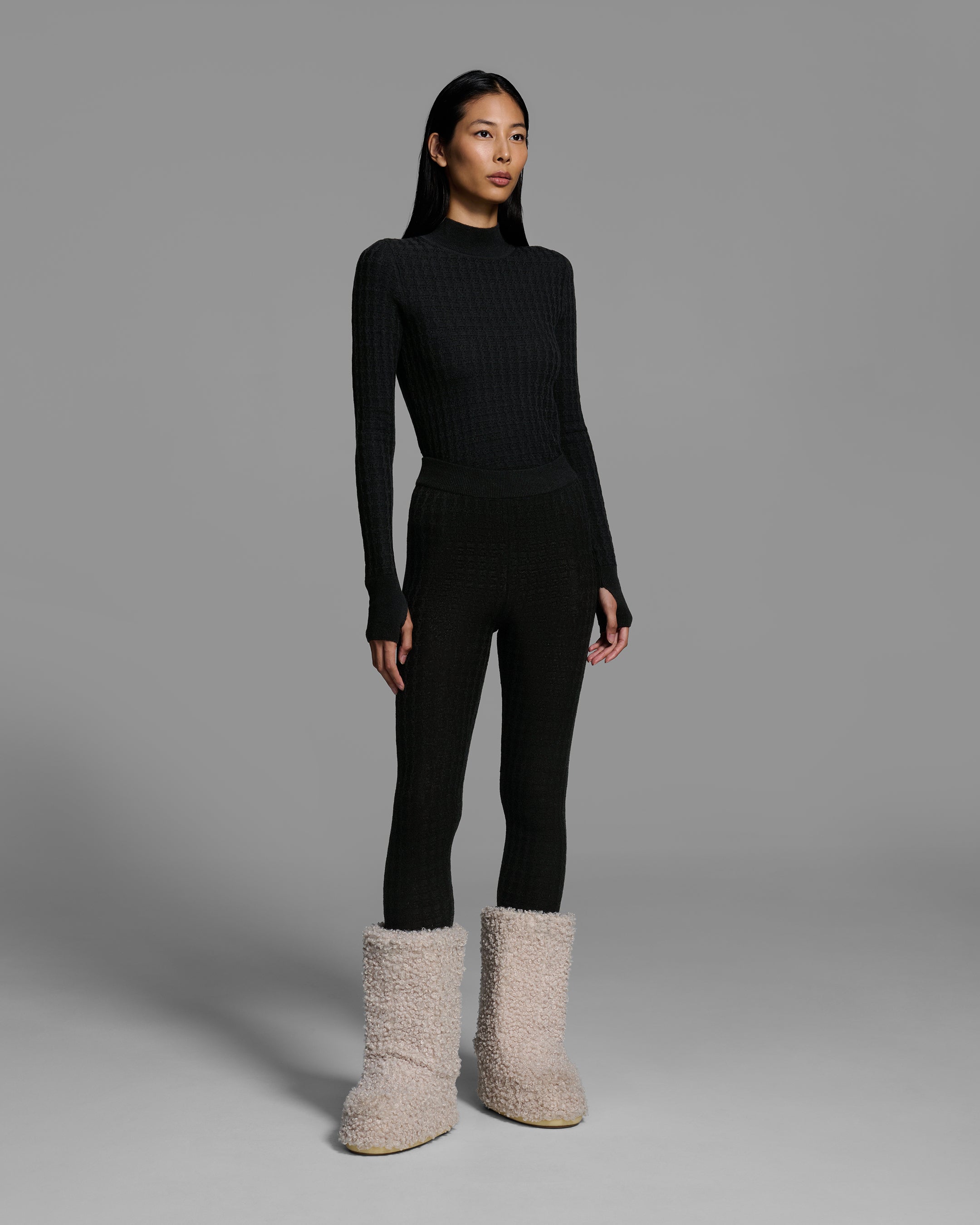 Woman wearing a textural knit base layer top and bottom in black. #color_onyx