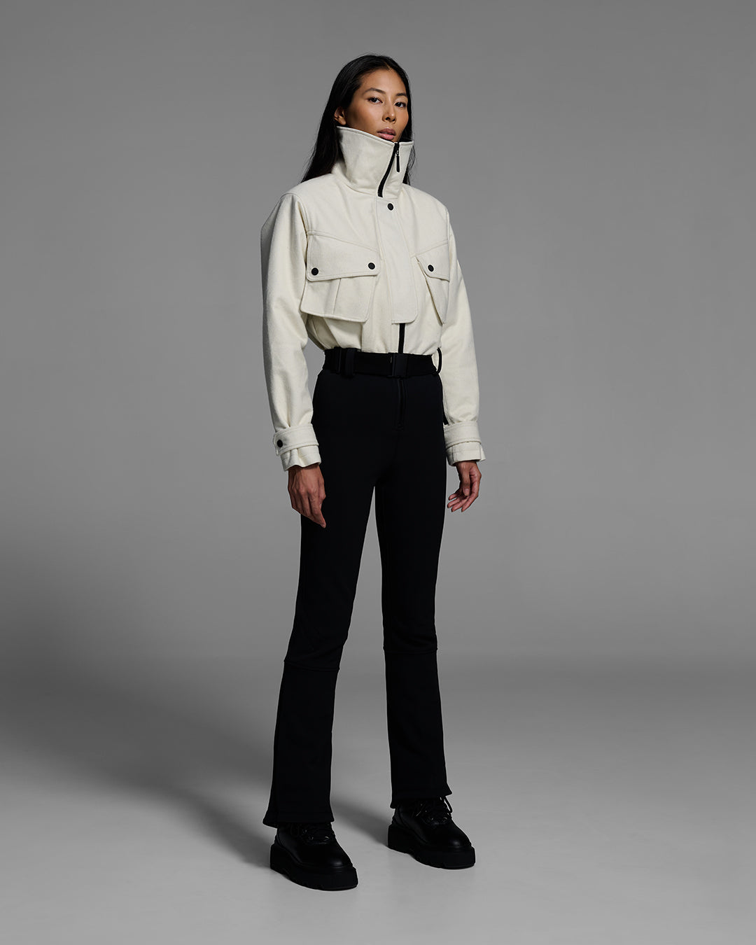 Woman wearing a natural white color wool top ski suit with belted waist and black 4-way stretch bottom. #color_natural / onyx