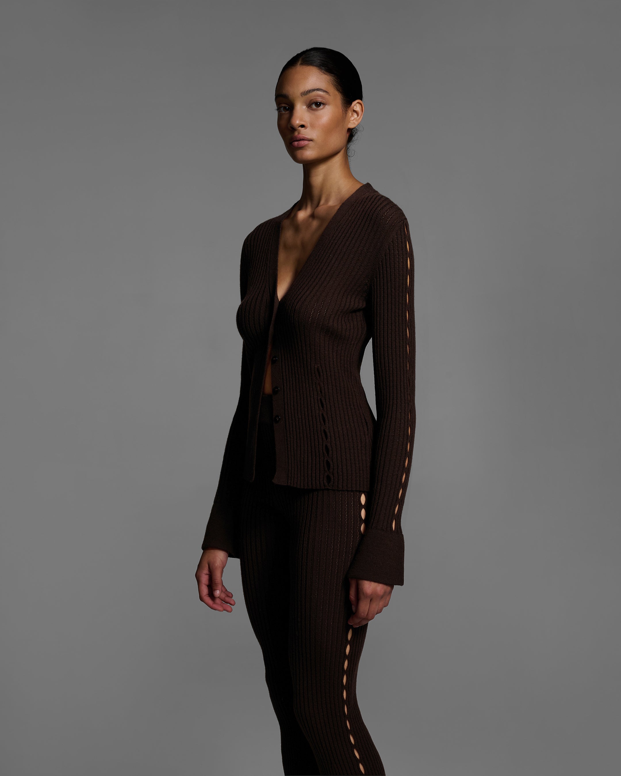 Woman wearing a chocolate brown knit sweater set with keyholes down the side of arms and legs. #color_chocolate