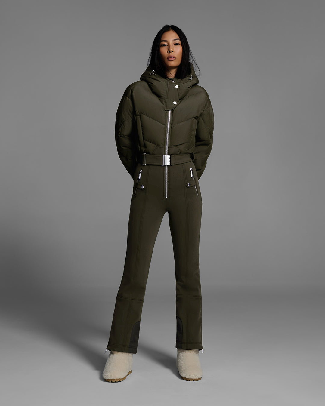 Female model wearing a belted khaki green color ski suit with down filled top and 4-way stretch bottom. #color_khaki