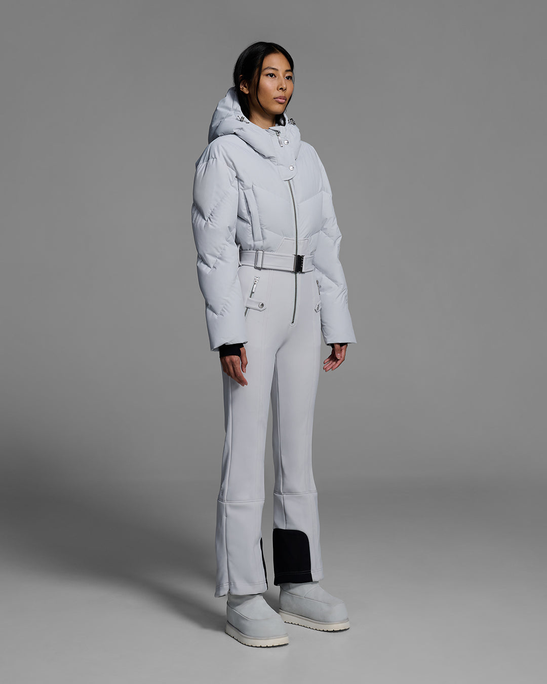 Female model wearing a belted smoke gray color ski suit with down filled top and 4-way stretch bottom. #color_smoke