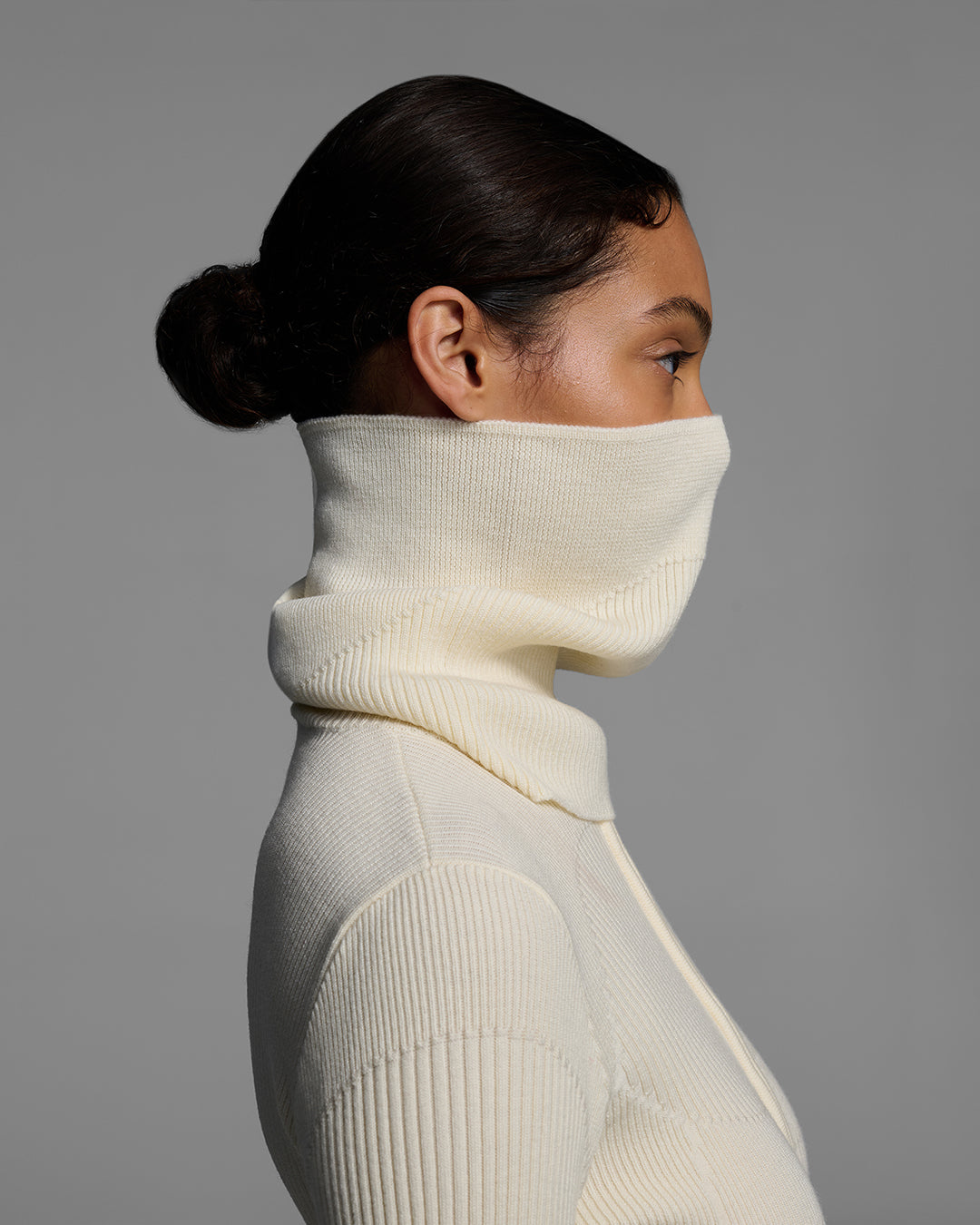 Side detail view of a female model wearing a knit wool buff in alabaster white with matching bodysuit. #color_alabaster