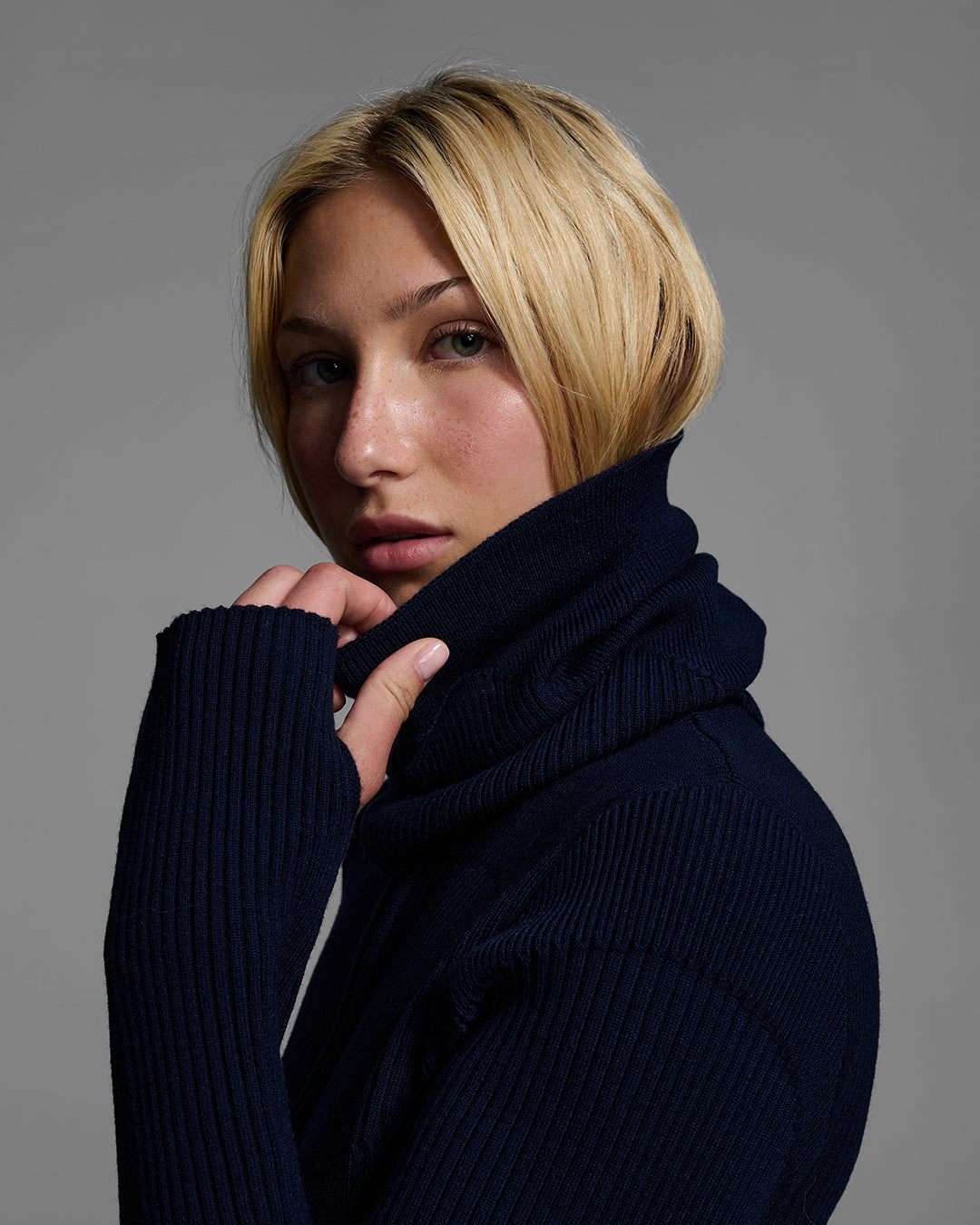 Side view of a female model wearing a knit wool buff in indigo blue with matching bodysuit. #color_indigo
