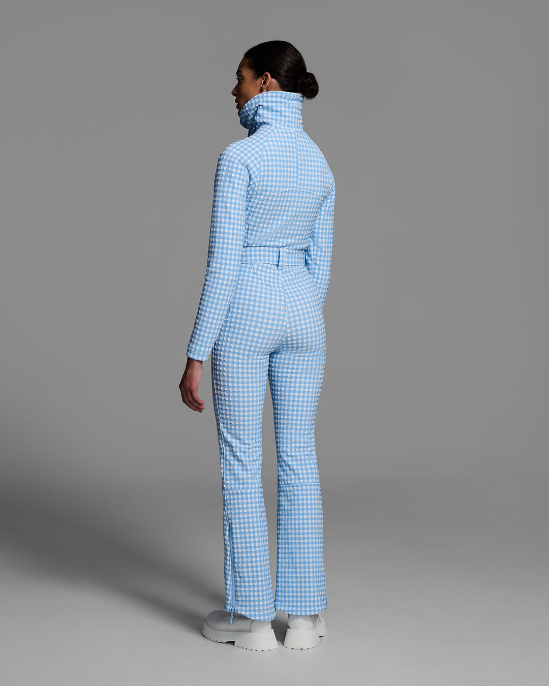 Back view of a female model wearing a belted cerulean blue and white gingham print ski suit #color_cerulean gingham