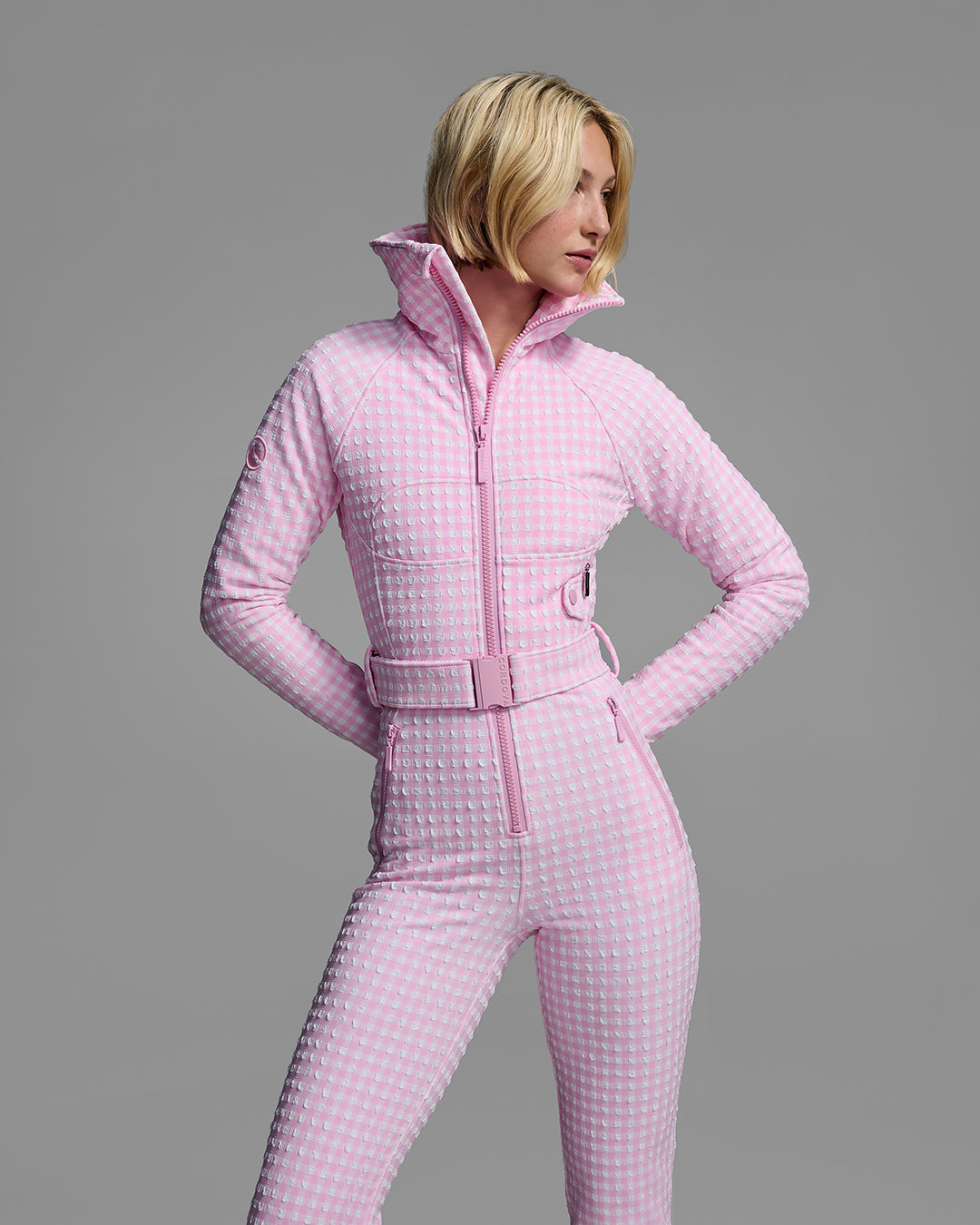 Detail view of a female model wearing a belted peony pink and white gingham print ski suit #color_peony gingham