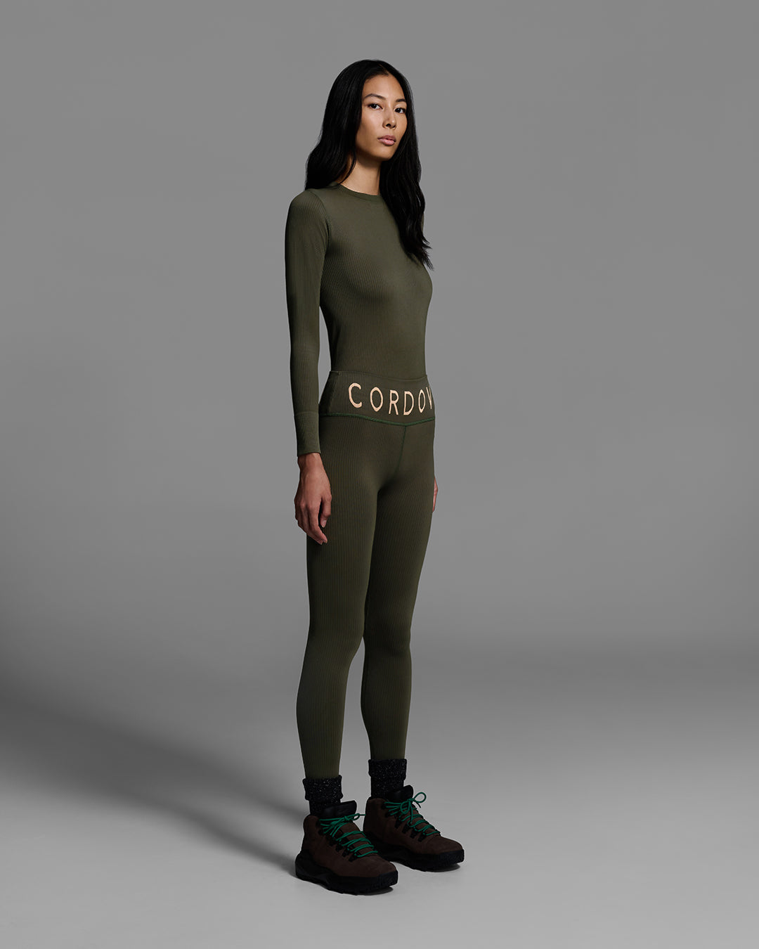 Female model wearing a matching ski base layer set in a compression knit fabric and khaki green color. #color_khaki