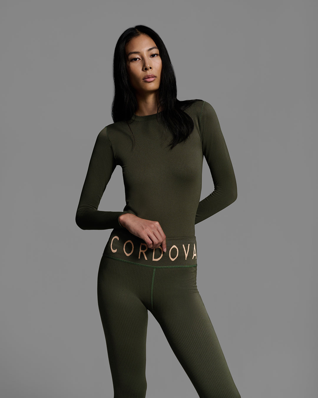 Detail front view of a female model wearing a matching ski base layer set in a compression knit fabric and khaki green color. #color_khaki