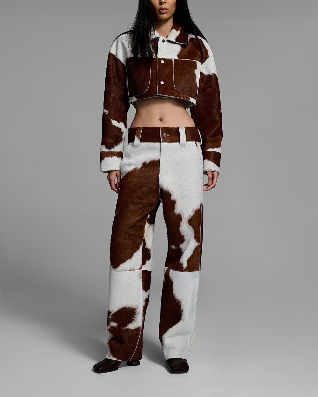 Female model wearing a cow print outfit on a gray background #color_cowhide