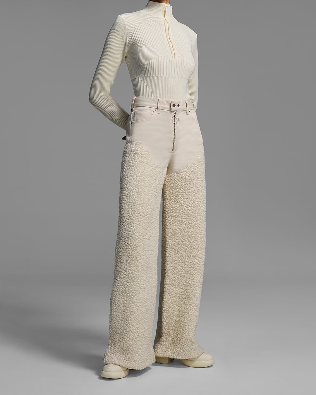 Front detail view of a female model wearing a resortwear pant with denim upper and sherpa leg in a natural wool fleece color. #color_natural