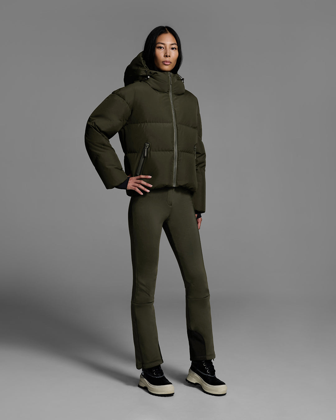 Female model wearing a classic down filled ski jacket in khaki green with a matching ski pant. #color_khaki