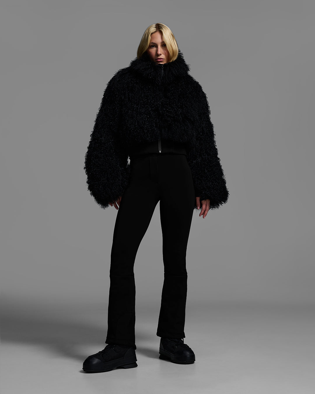 Female model wearing a black color shearling jacket with matching ski pant. #color_onyx