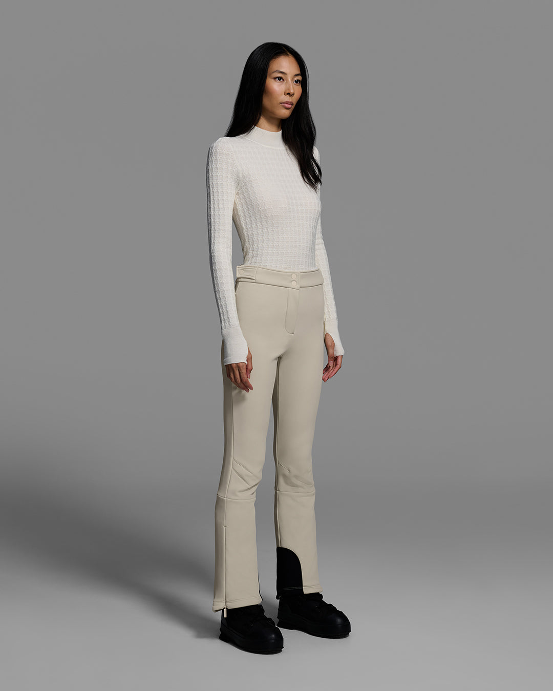 Woman wearing a 4-way stretch ski pant in birch inspired tan and a off white base layer sweater. #color_birch