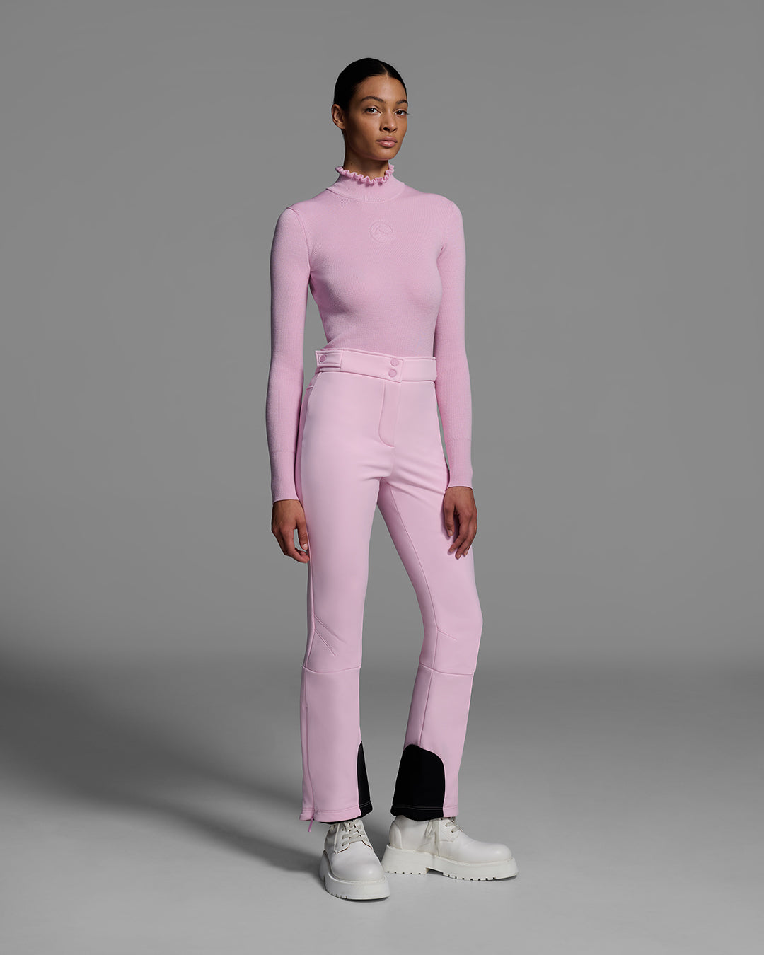 Woman wearing a 4-way stretch ski pant in peony pink and a matching base layer top. #color_peony