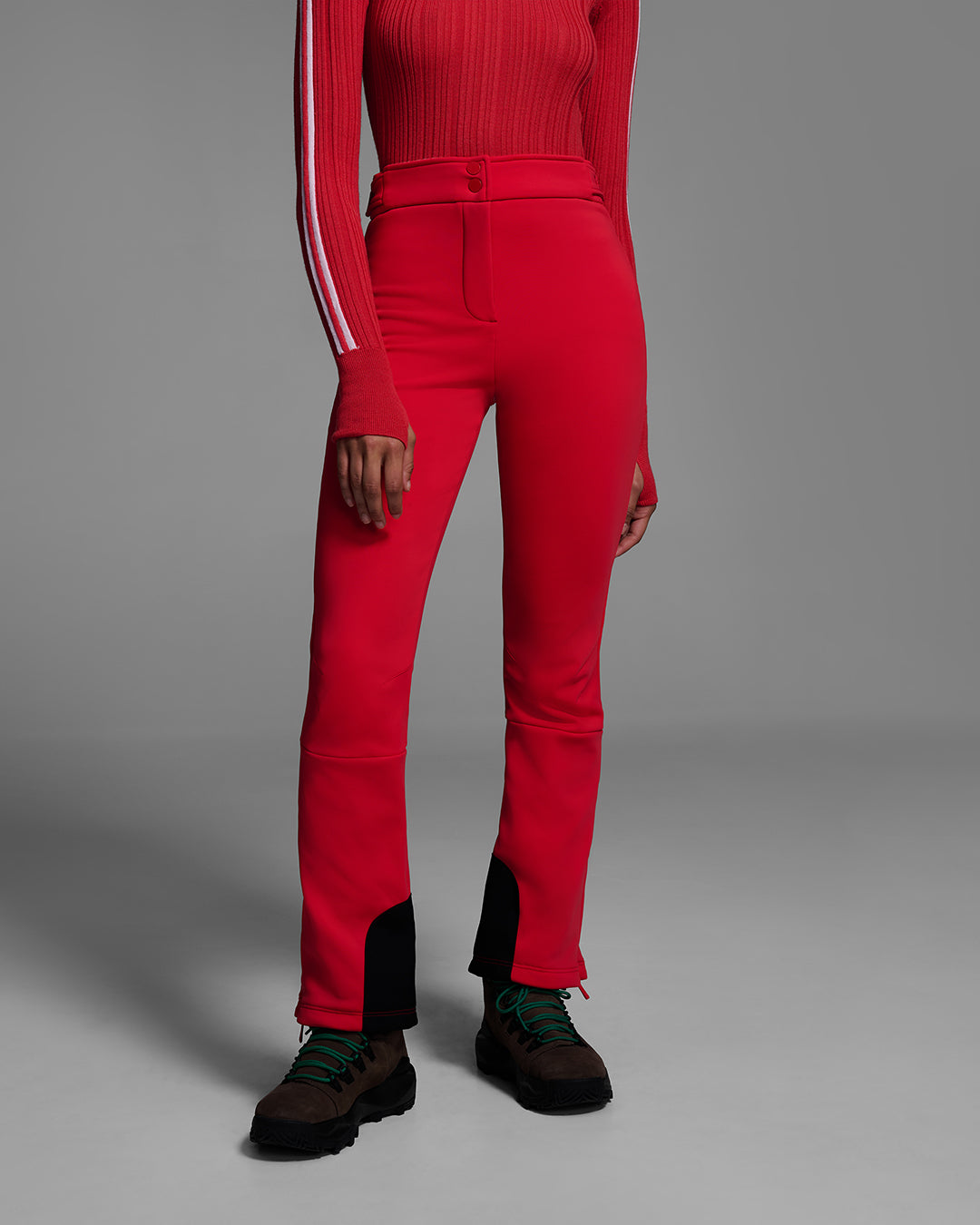 Detail view of a woman wearing  a 4-way stretch ski pant in poppy red and a matching red ski sweater. #color_poppy