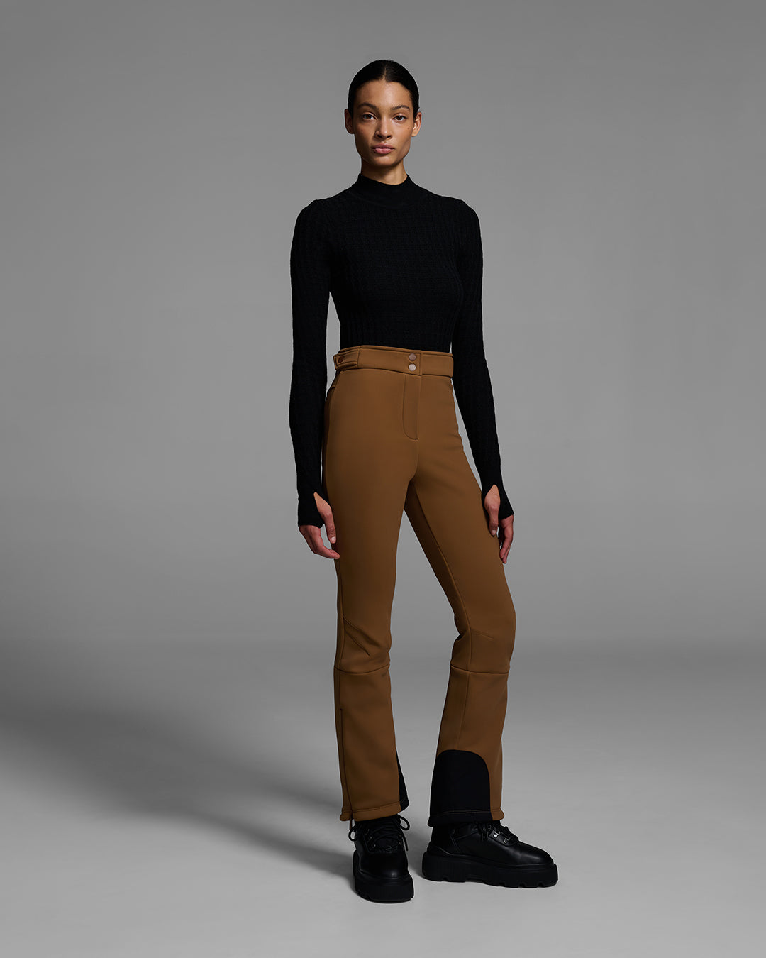 Woman wearing a 4-way stretch ski pant in sepia brown and a black base layer top. #color_sepia