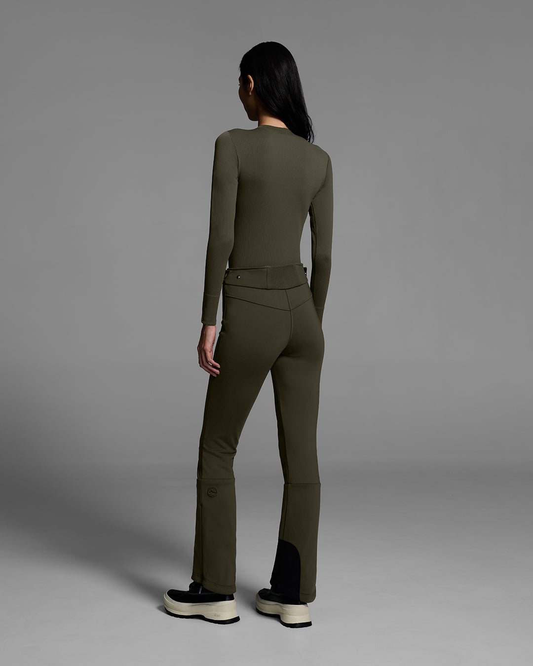 Back view of a woman wearing a 4-way stretch ski pant in khaki green with a matching base layer top. #color_khaki