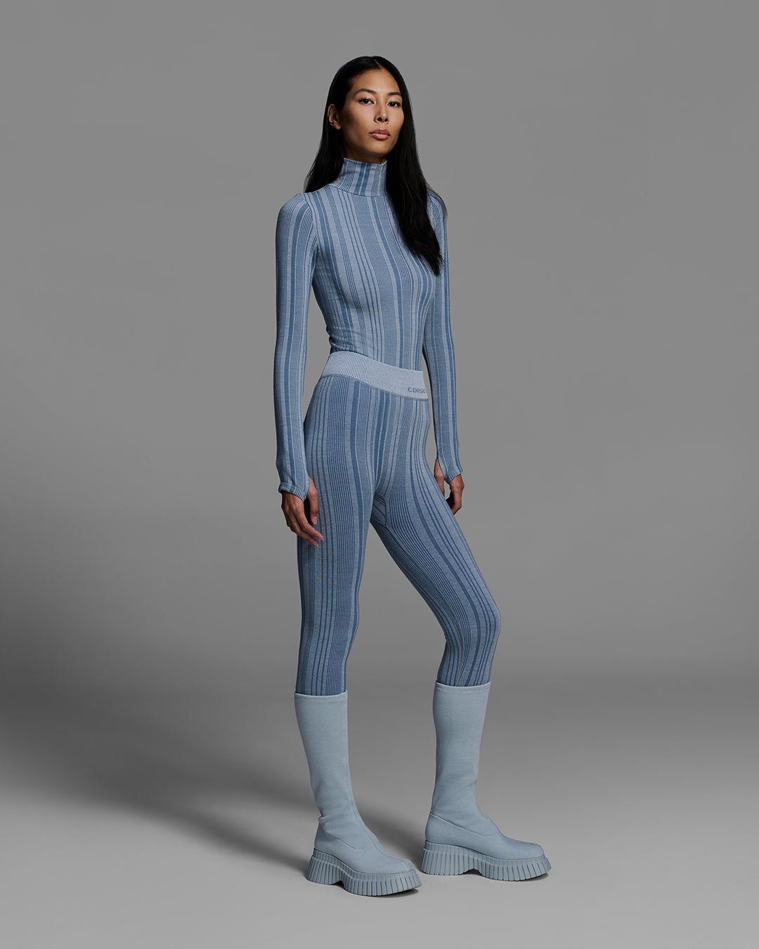Woman wearing a slate blue color turtleneck and matching pant base layer set made of merino wool blend. #color_slate