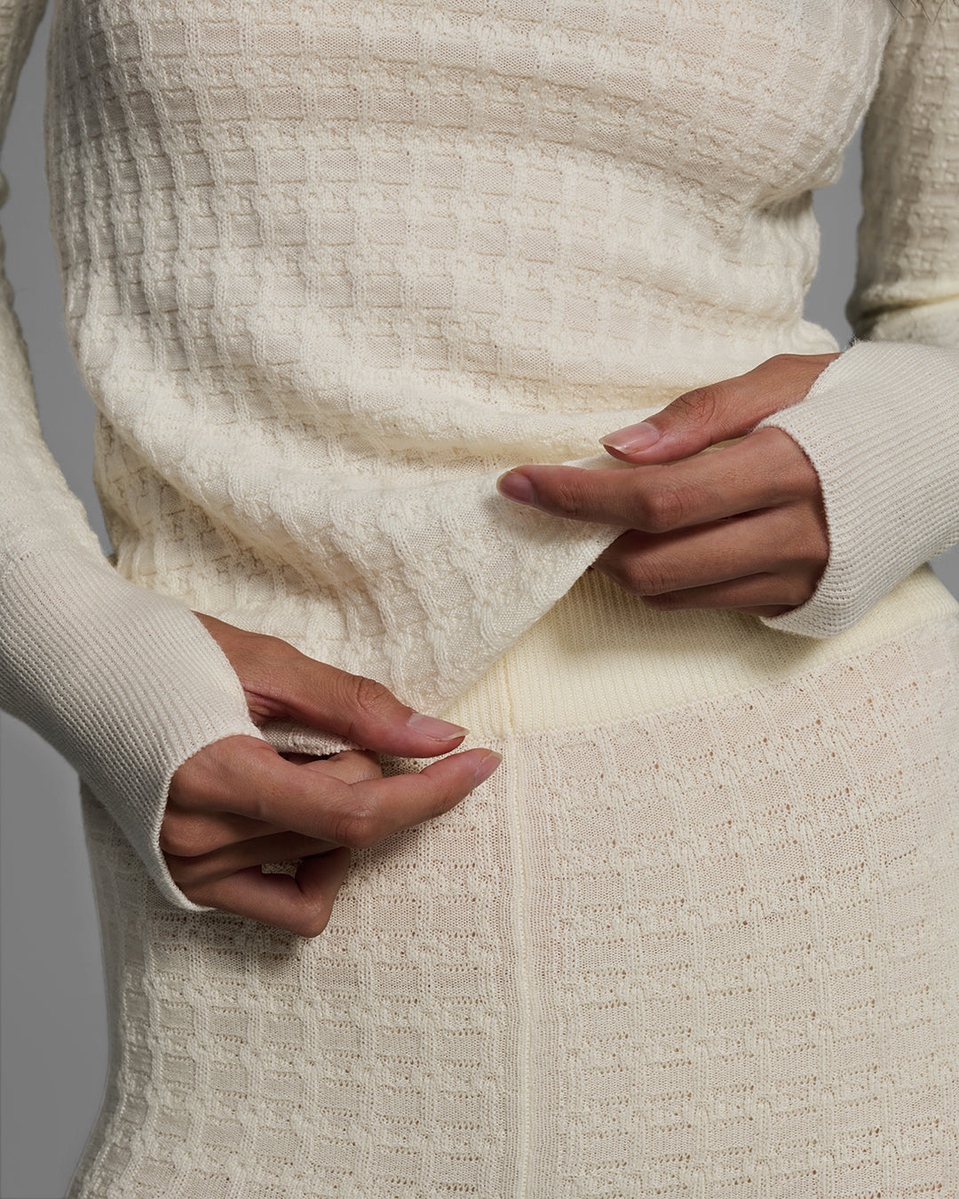 Detail view of a woman wearing a textural knit base layer top and bottom in off-white. #color_alabaster
