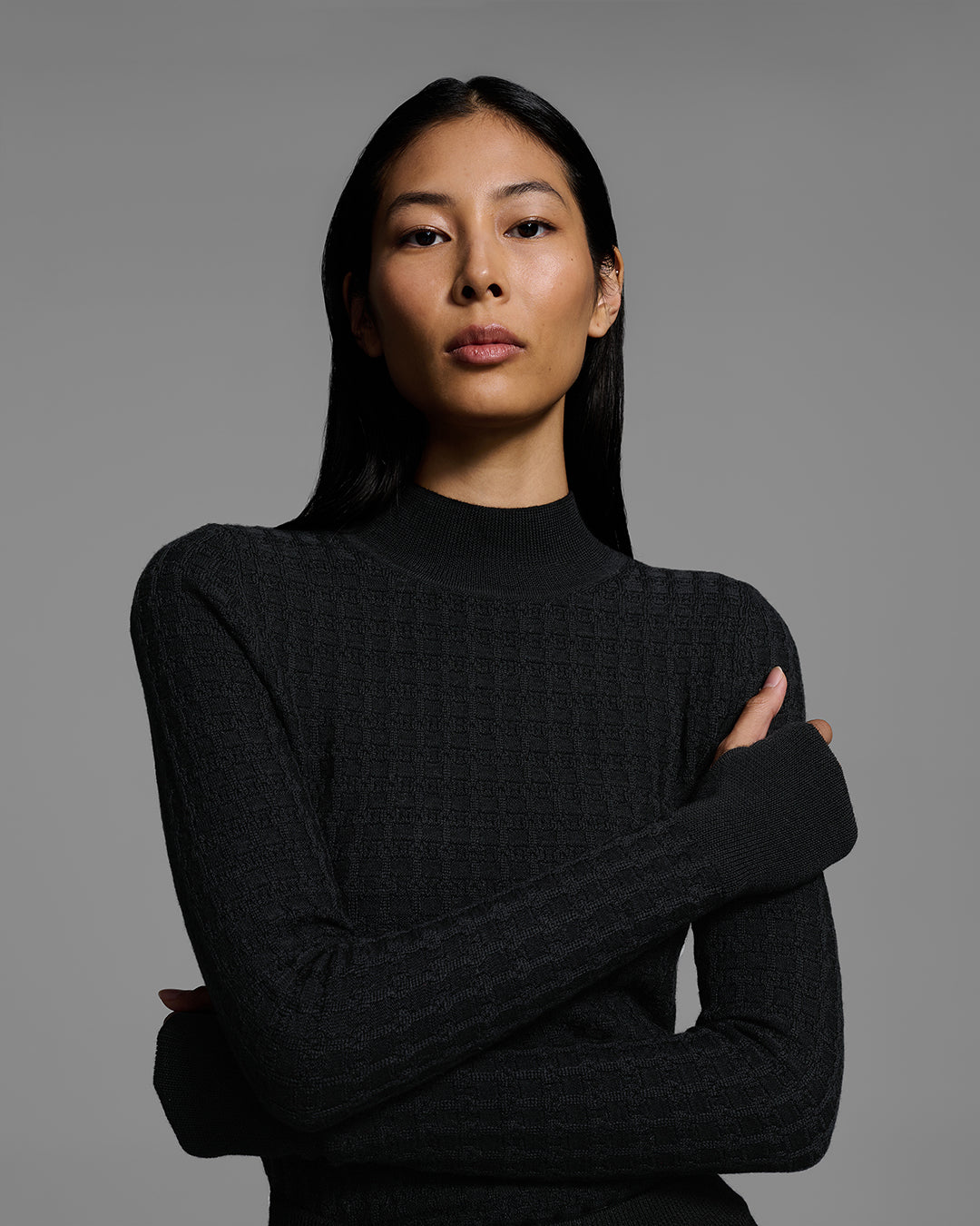Detail view of a woman wearing a textural knit base layer top in black. #color_onyx