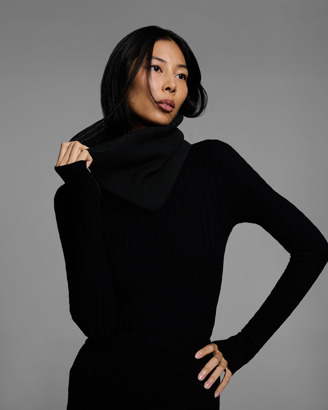 Close up of a woman wearing a black ski buff made of merino wool with matching base layer top. #color_onyx